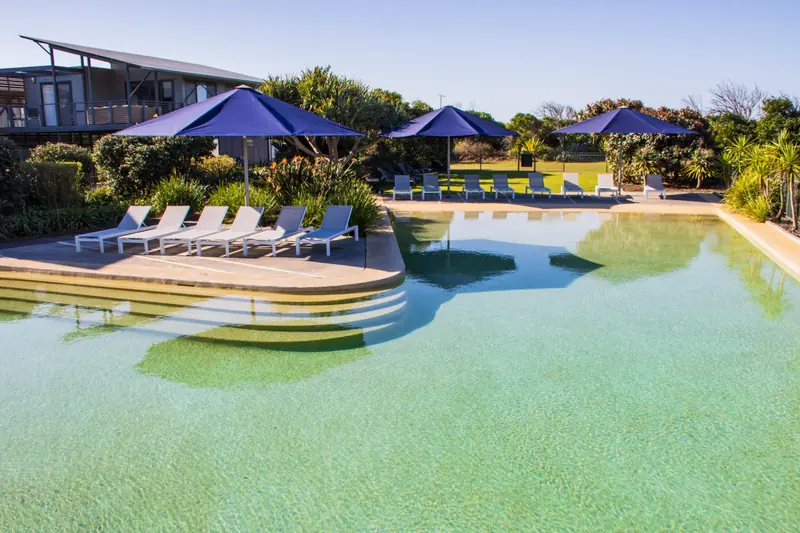 Resort swimming pool with wide entry steps and sun lounges