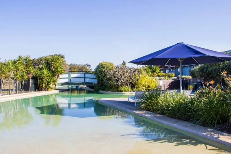 Footbridge and shaded sun lounges beside the resort swimming pool