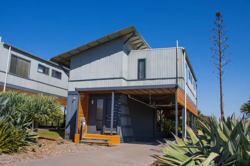 Two-storey beach house surrounded by coastal gardens